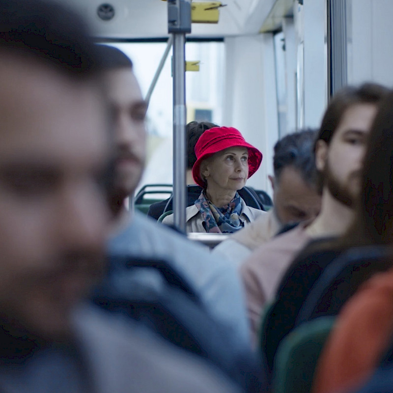 Dame mit roten Hut in einem gefüllten Bus